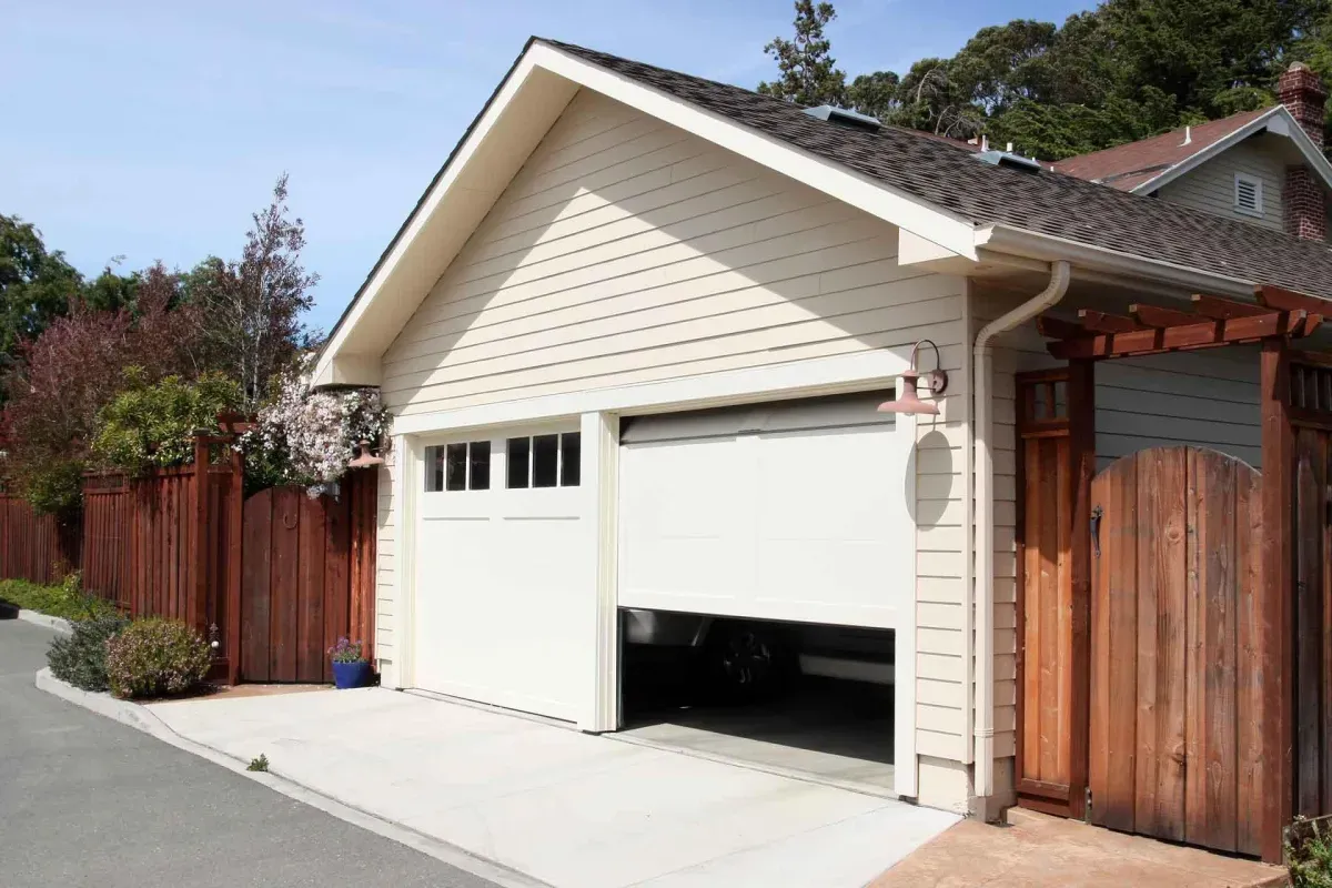 Modern garage with open door and plants nearby.