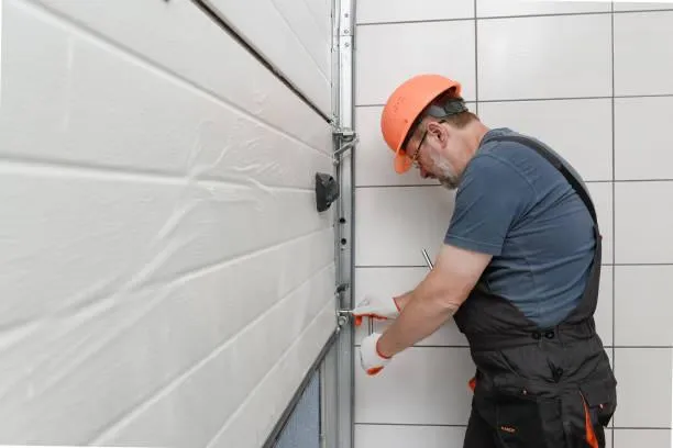 A worker in an orange hard hat repairing a garage door