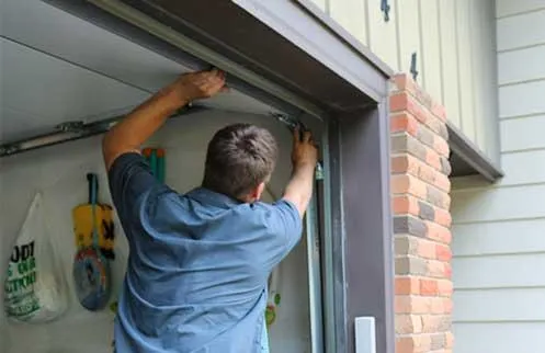 Man repairing a garage door with tools.
